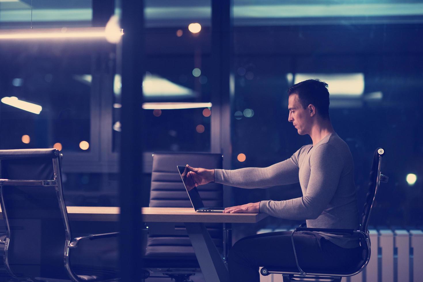 man working on laptop in dark office photo