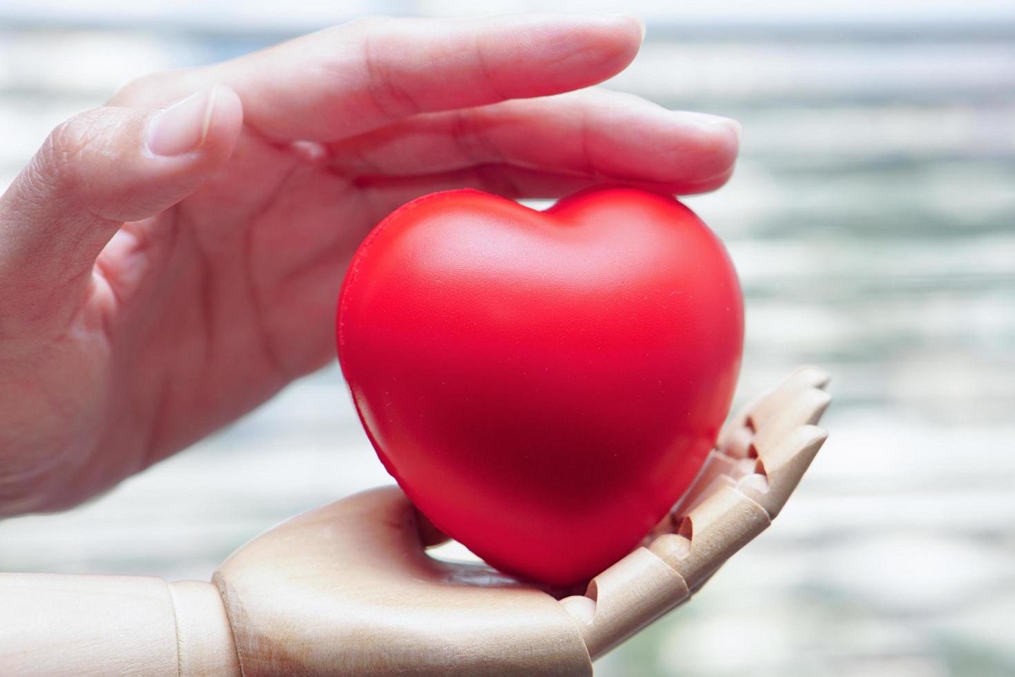 Human hand and robot hand is holding a red heart show unity with two hands together. Concept of Artificial intelligence, technology, join forces, and progress future. photo