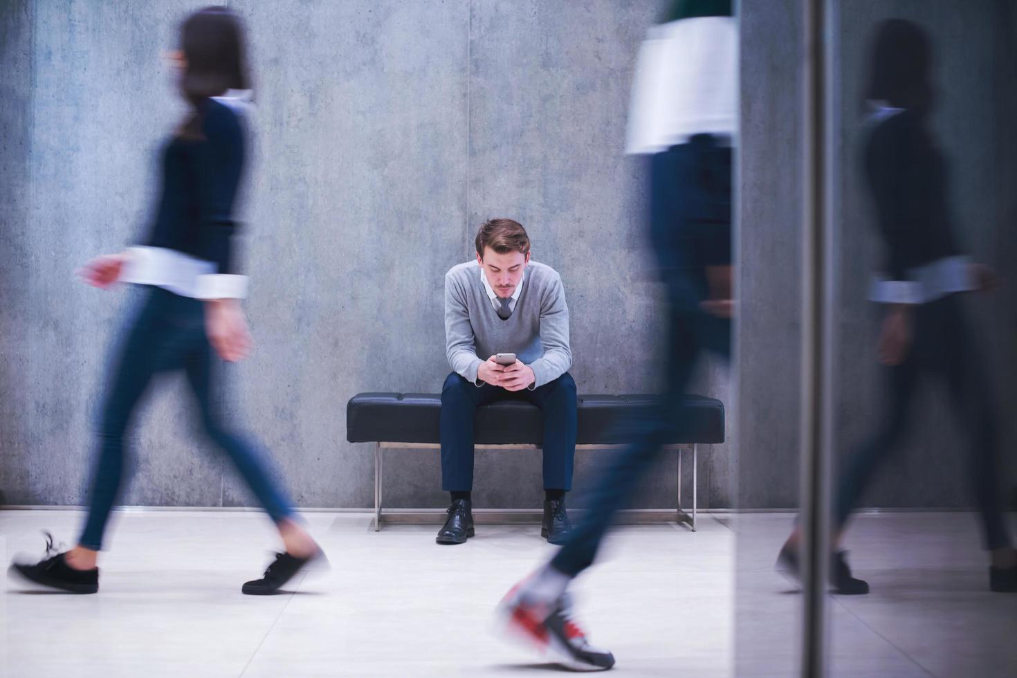 businessman using mobile phone while sitting on the bench photo