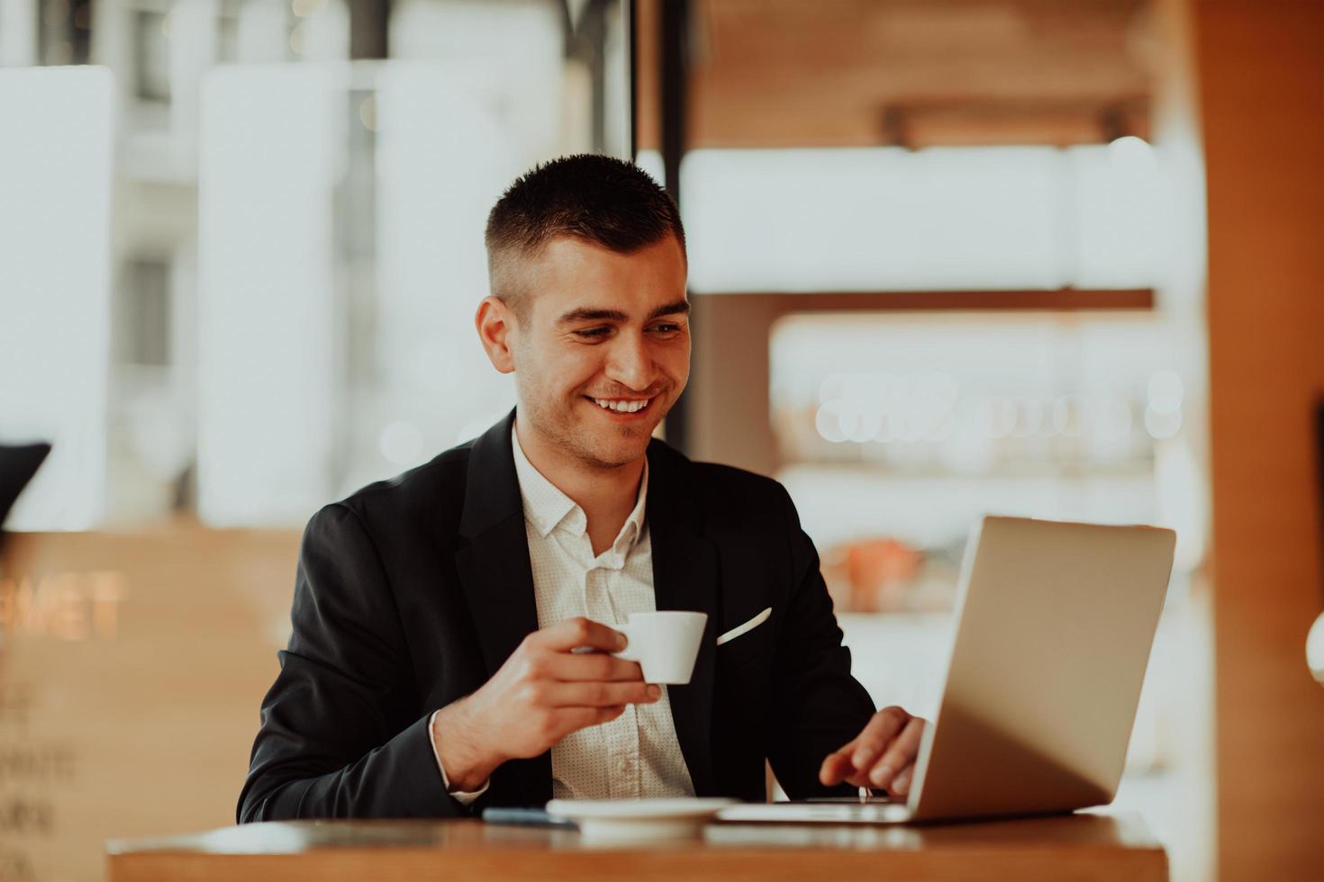 feliz hombre de negocios sentado en la cafetería con laptop y smartphone. foto