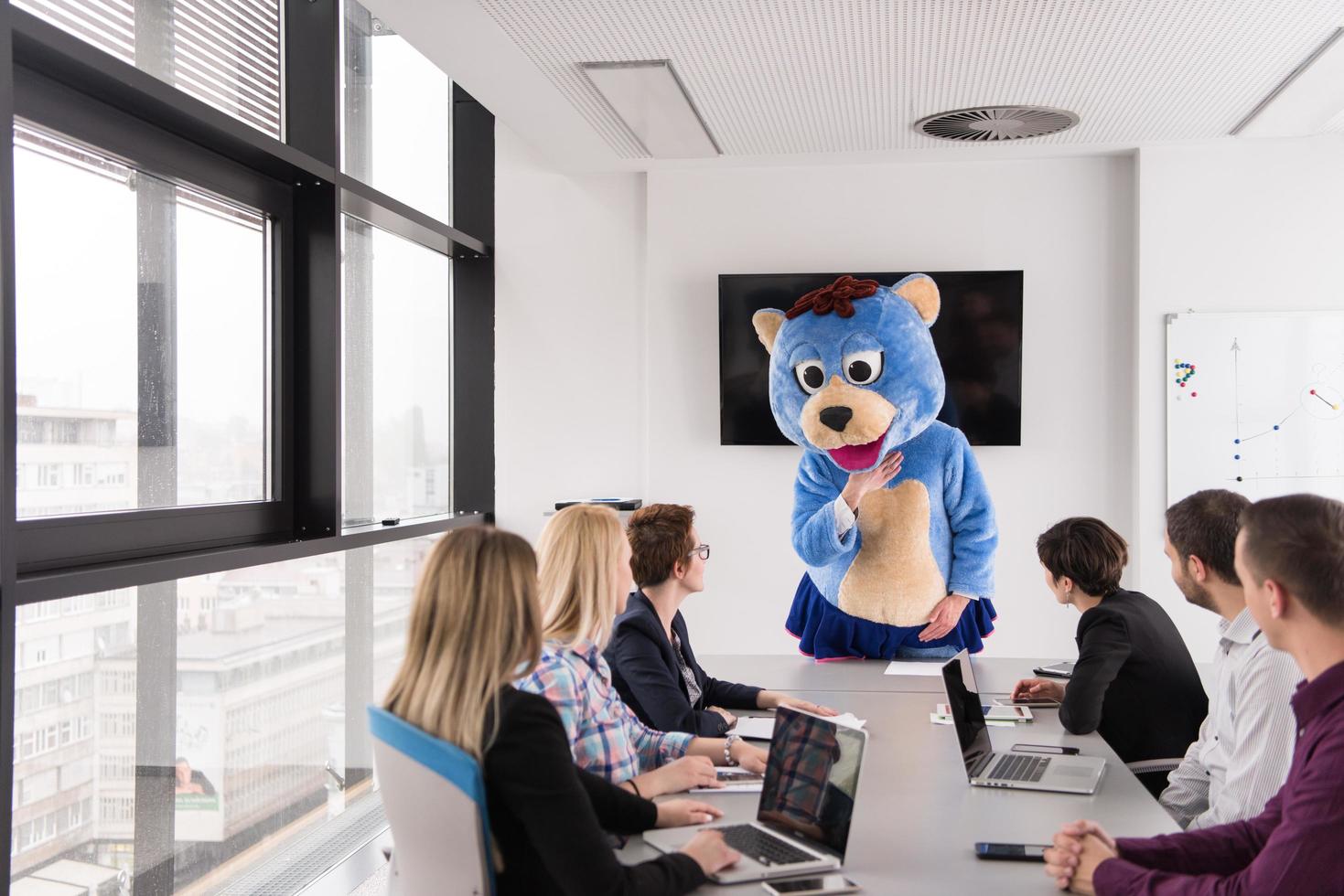 boss dresed as bear having fun with business people in trendy office photo