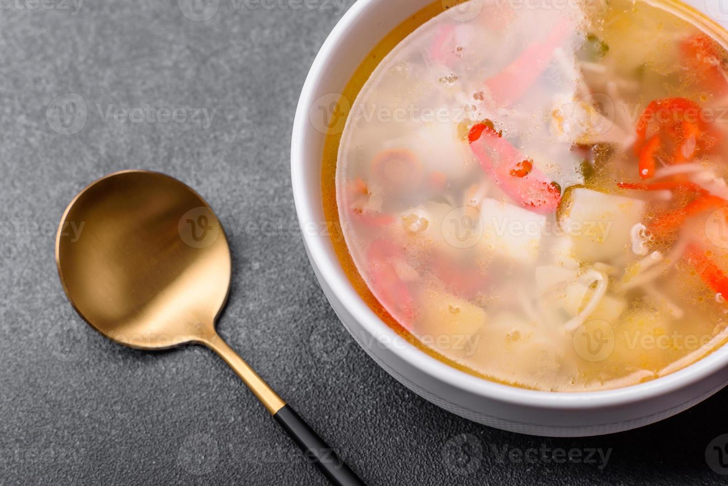 Closeup of a bowl of chicken noodle and vegetable soup on a concrete table photo