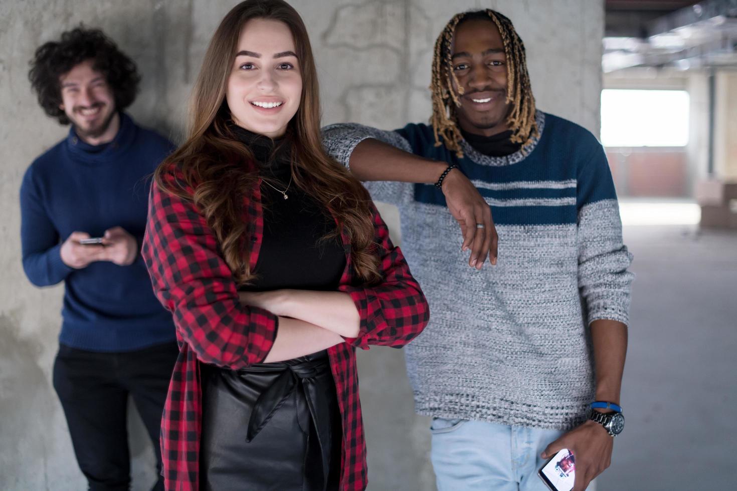 casual multiethnic business team using mobile phones in front of a concrete wall photo