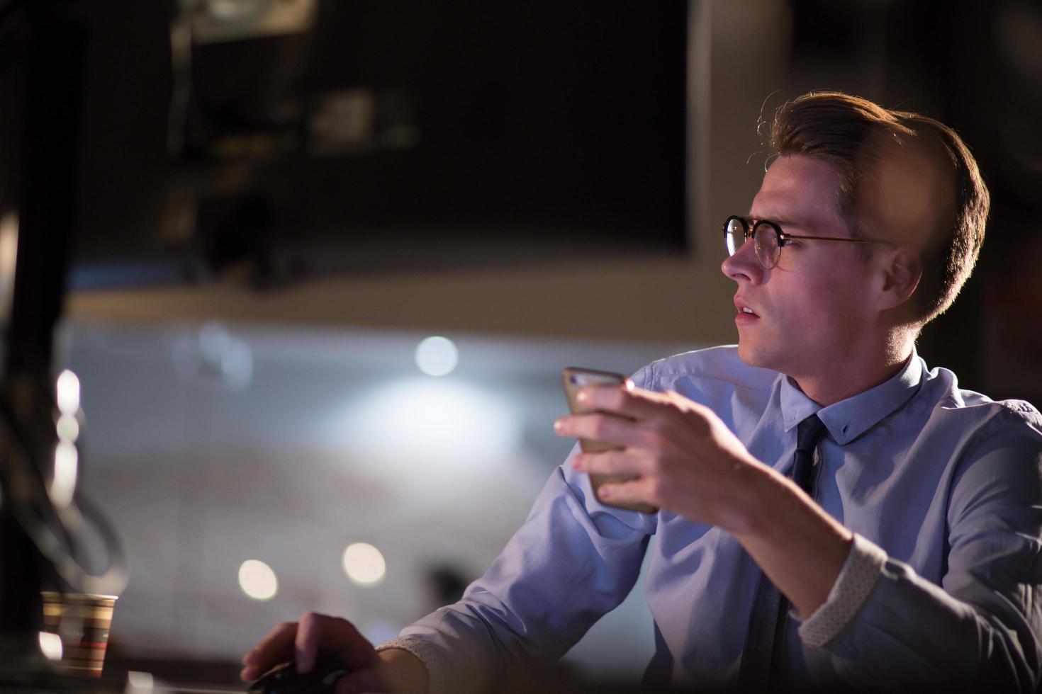 man using mobile phone in dark office photo