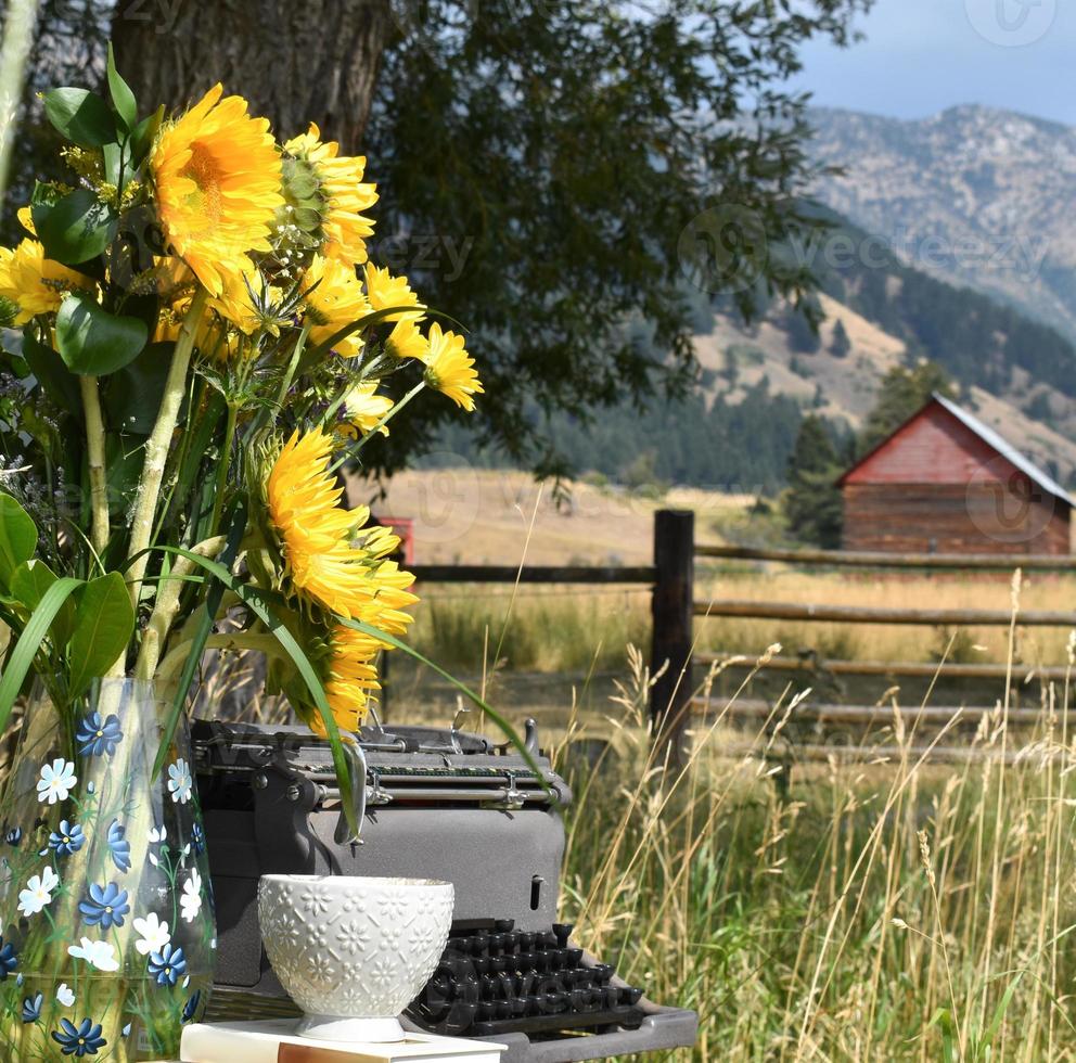 Typewriter In A Pasture With Sunflowers, A Stack Of Books, And A Tea Cup photo