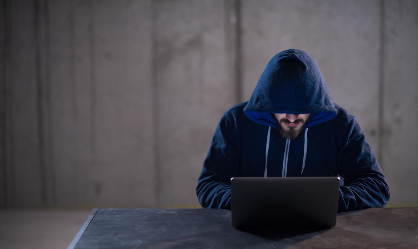 talented hacker using laptop computer while working in dark office photo