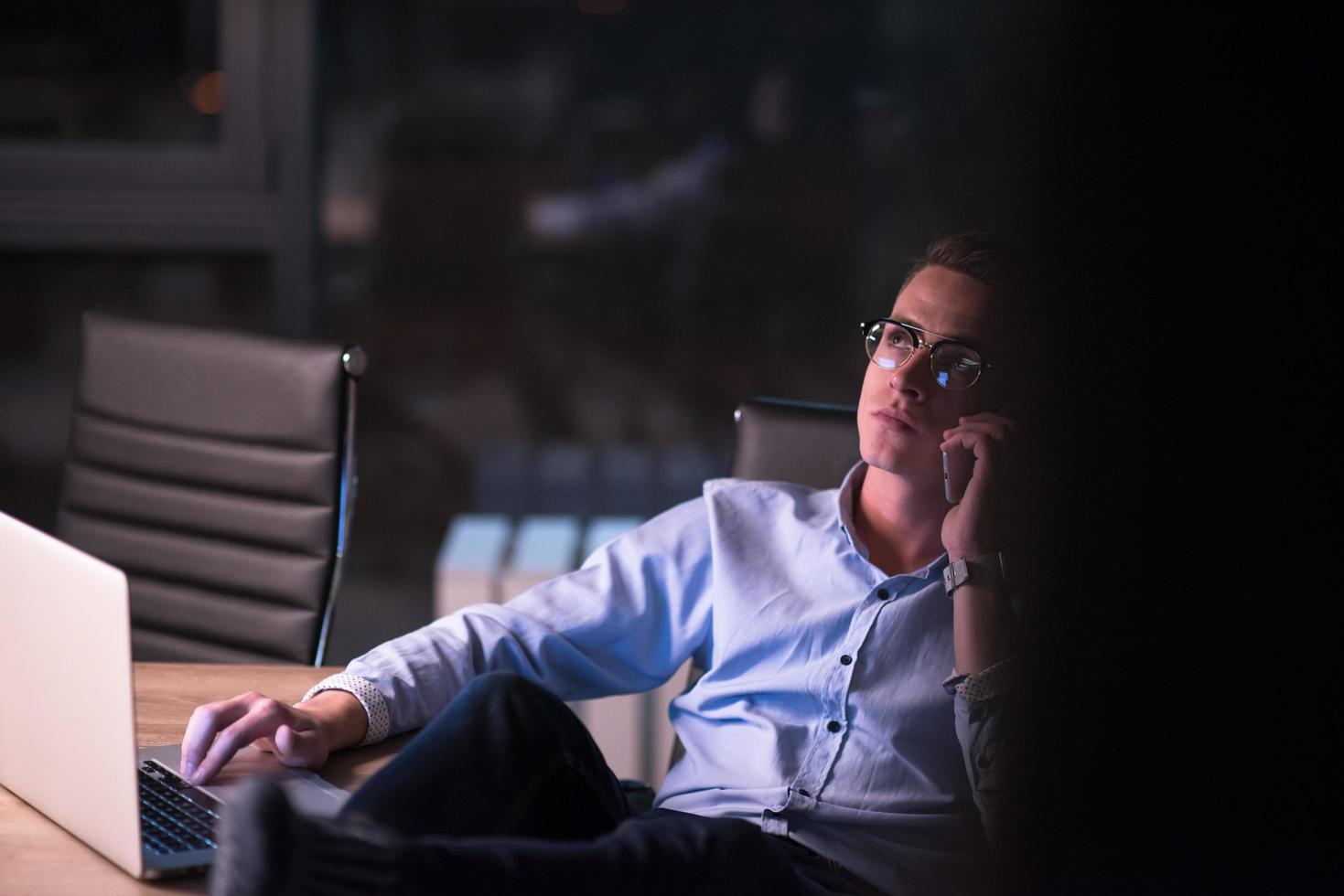 businessman using mobile phone in dark office photo
