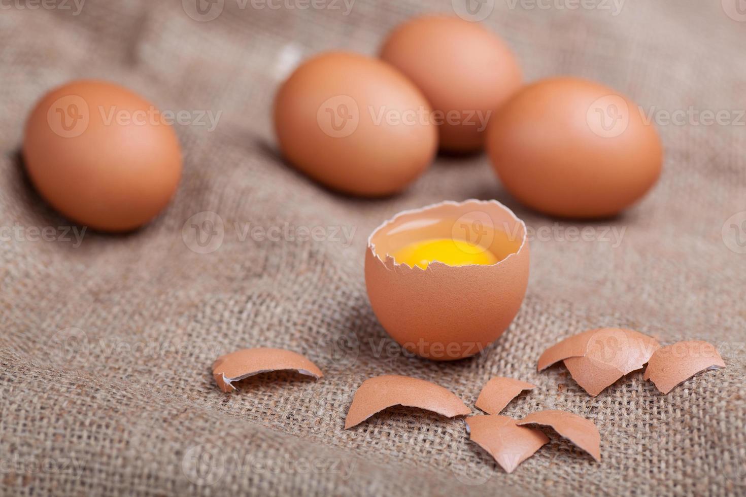 Fresh eggs on sacking, broken eggshell, yolk photo