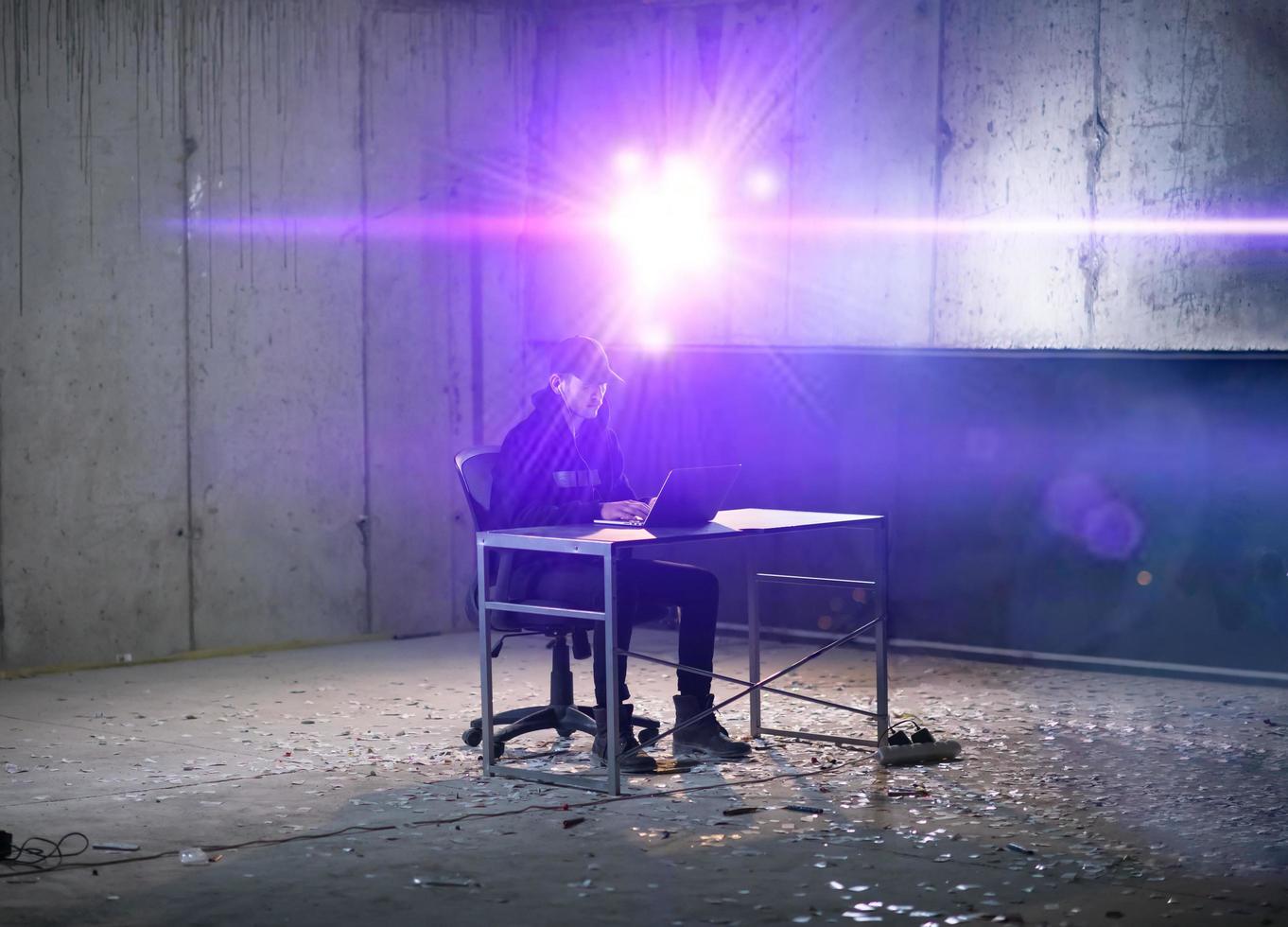 young talented hacker using laptop computer while working in dark office photo