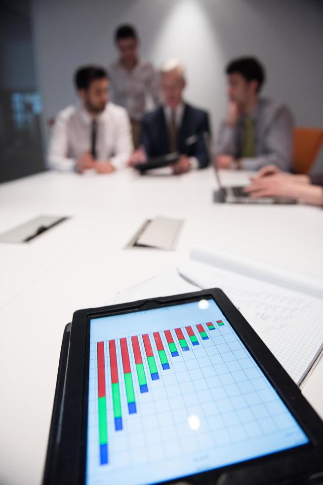 close up of touchpad with analytics documents at business meeting photo