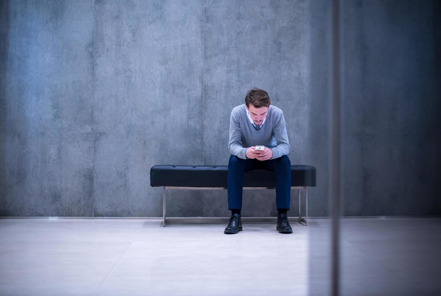 hombre de negocios que usa un teléfono inteligente mientras está sentado en el banco foto