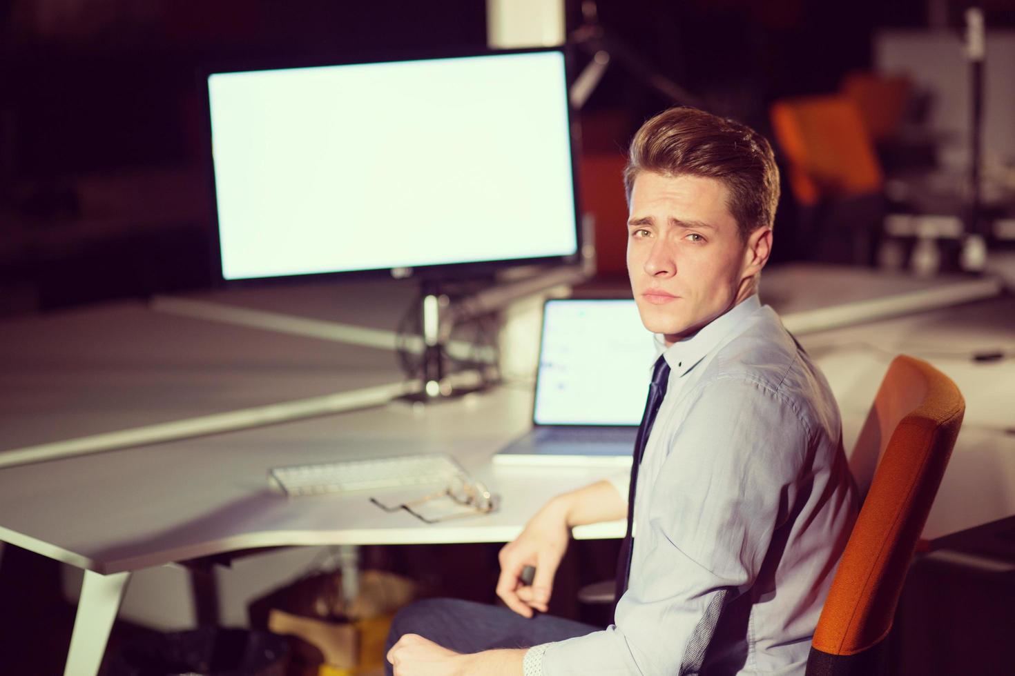 man working on computer in dark office photo