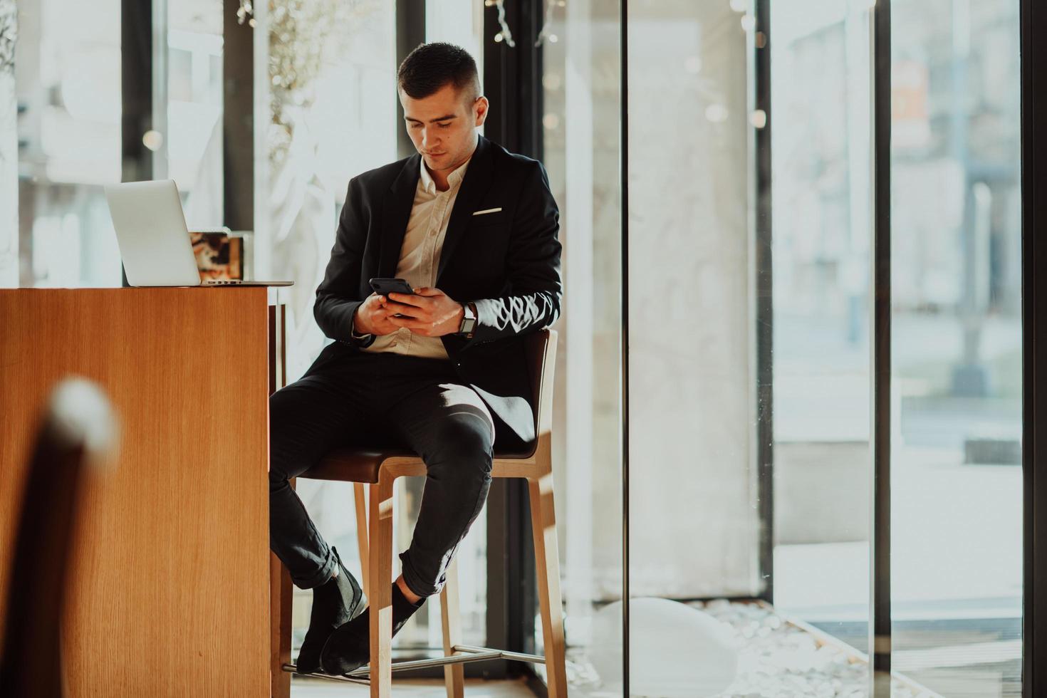 feliz hombre de negocios sentado en la cafetería con laptop y smartphone. foto