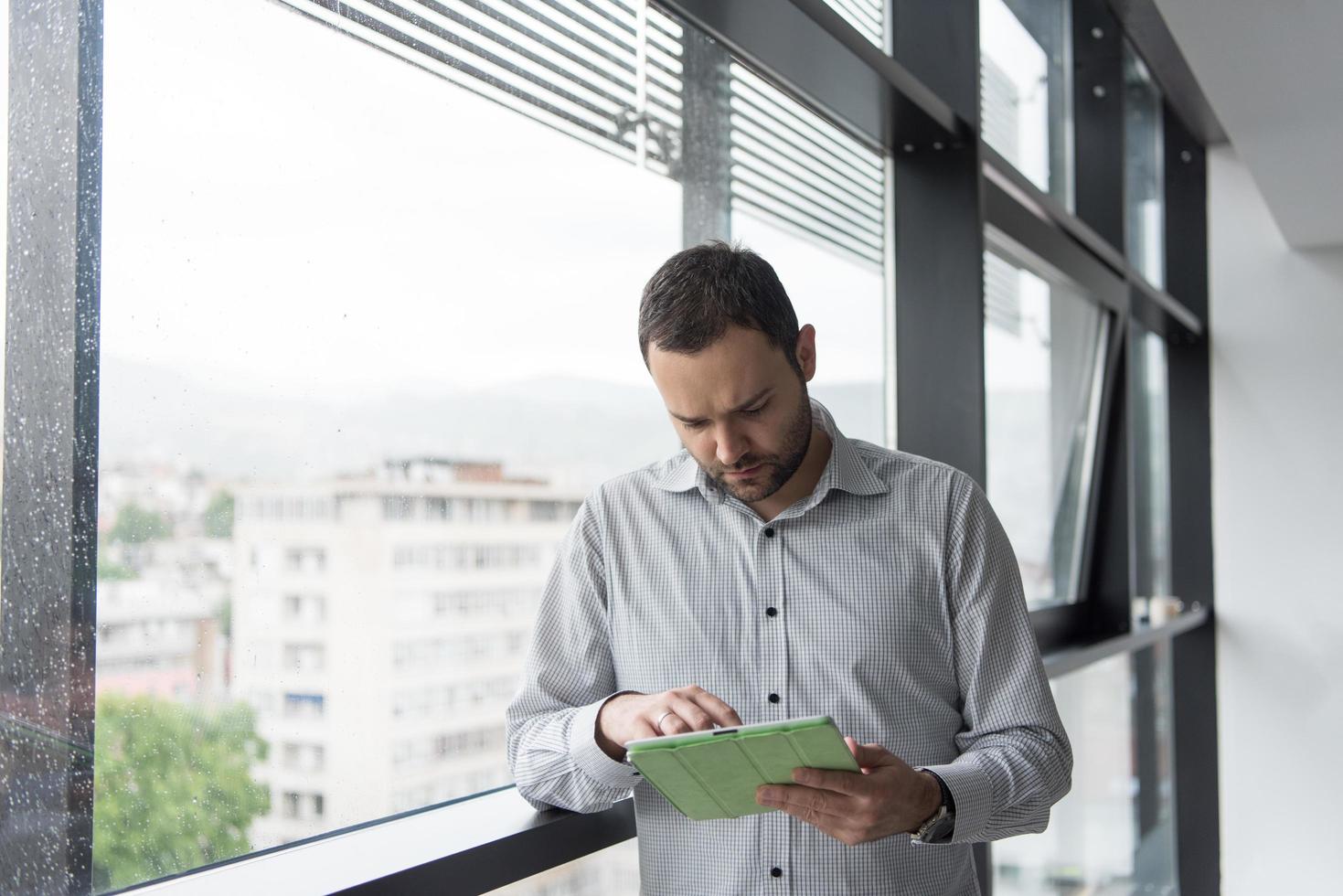 Businessman Using Tablet In Office Building by window photo