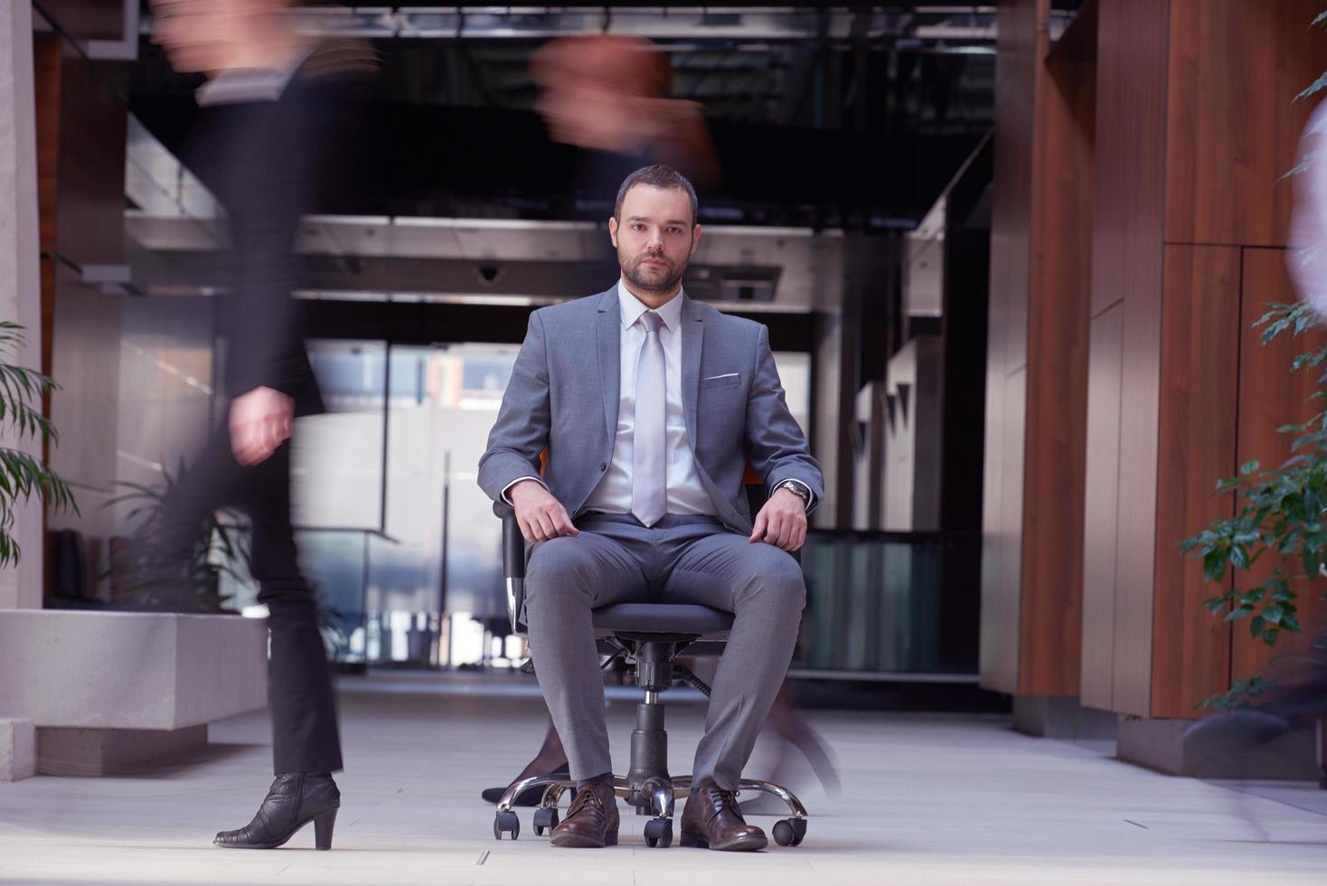 business man sitting in office chair, people group  passing by photo