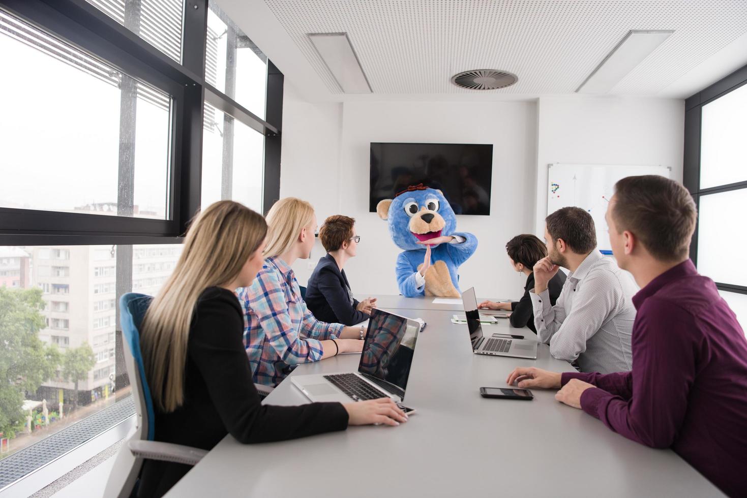 boss dresed as bear having fun with business people in trendy office photo
