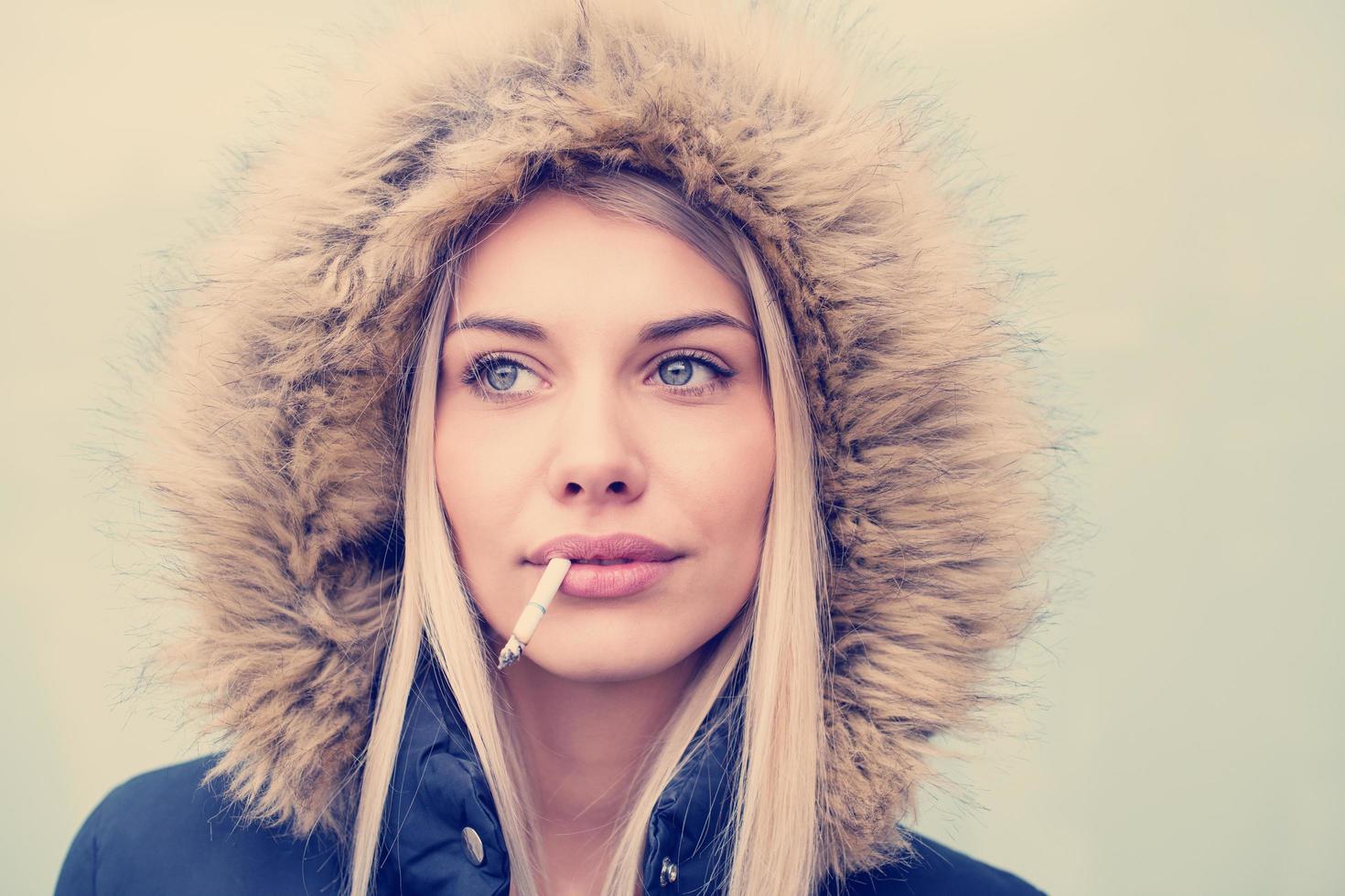 portrait of young blonde girl with cigarette in the mouth photo
