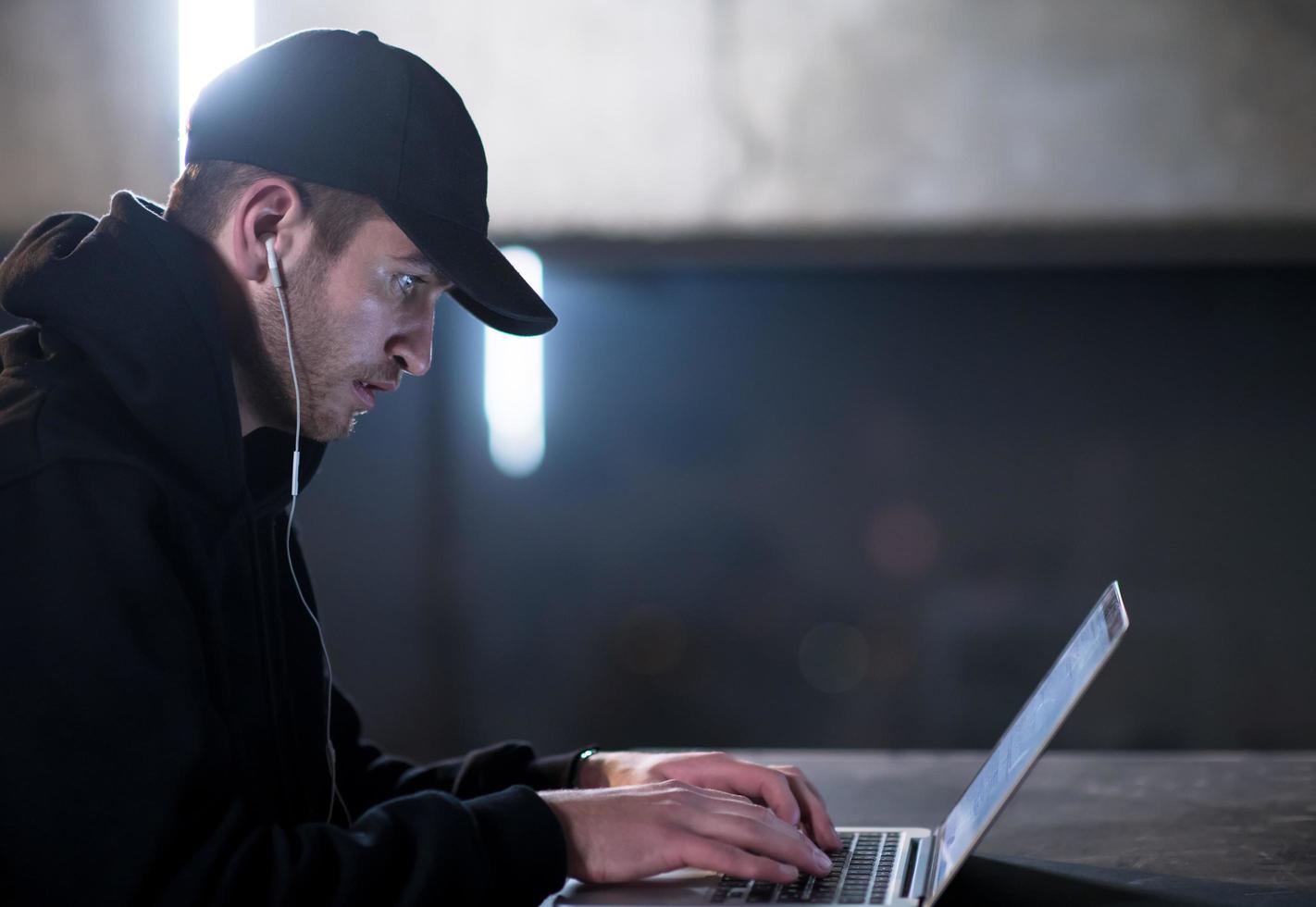 talented hacker using laptop computer while working in dark office photo