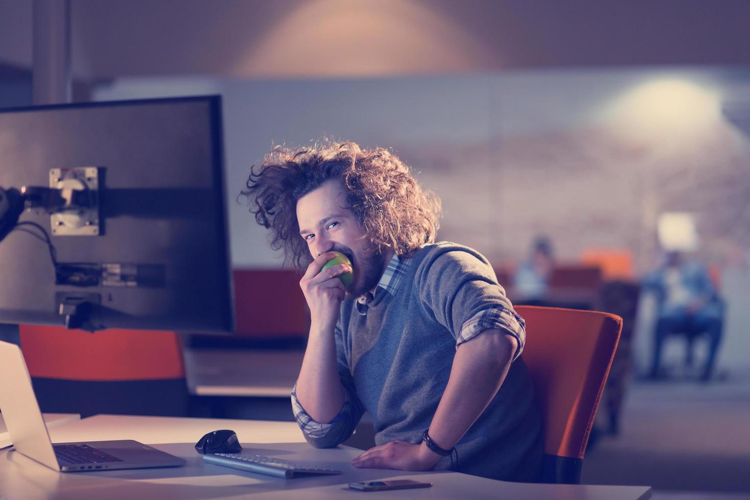 man eating apple in his office photo