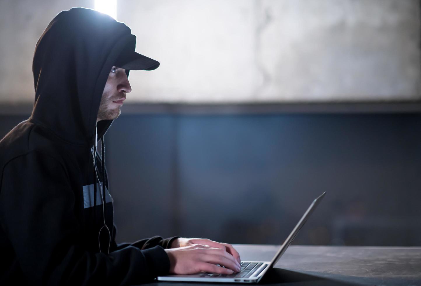 talented hacker using laptop computer while working in dark office photo
