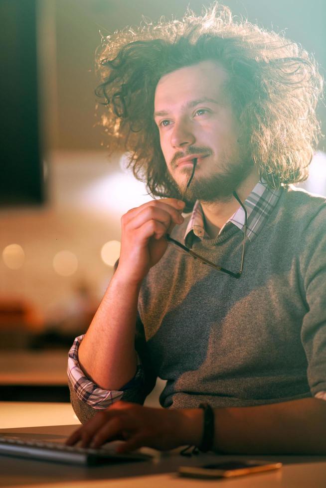 man working on computer in dark office photo