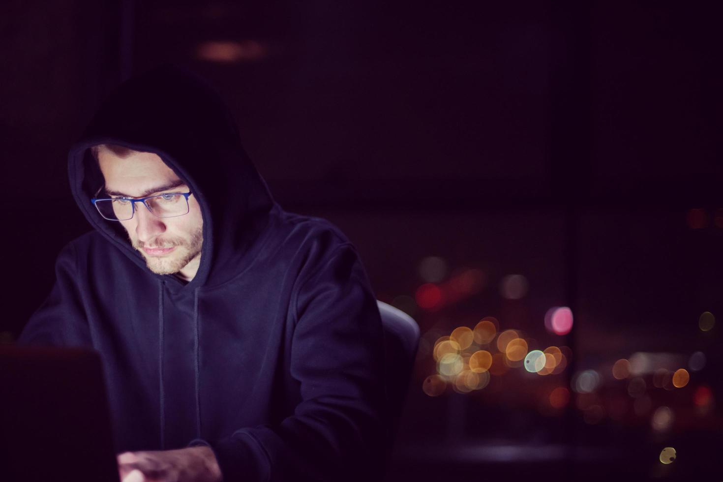 hacker using laptop computer while working in dark office photo