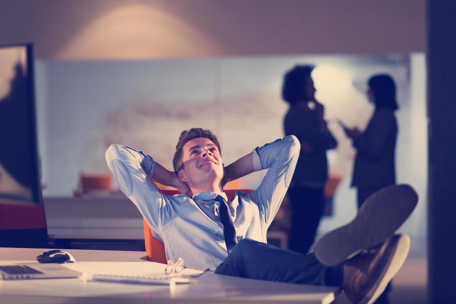businessman sitting with legs on desk at office photo