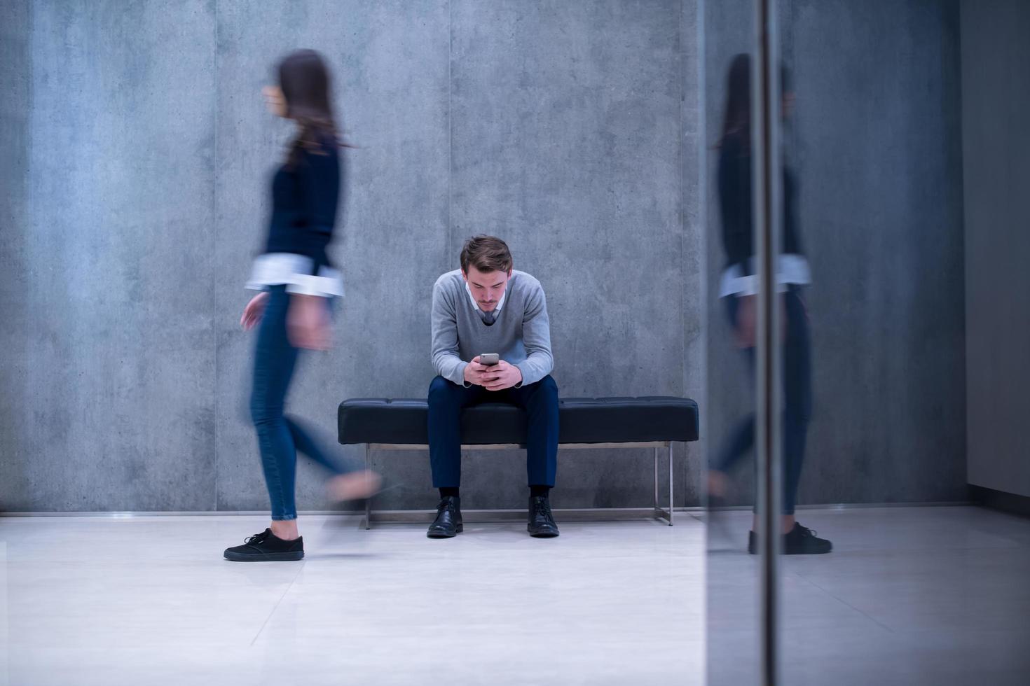 businessman using mobile phone while sitting on the bench photo