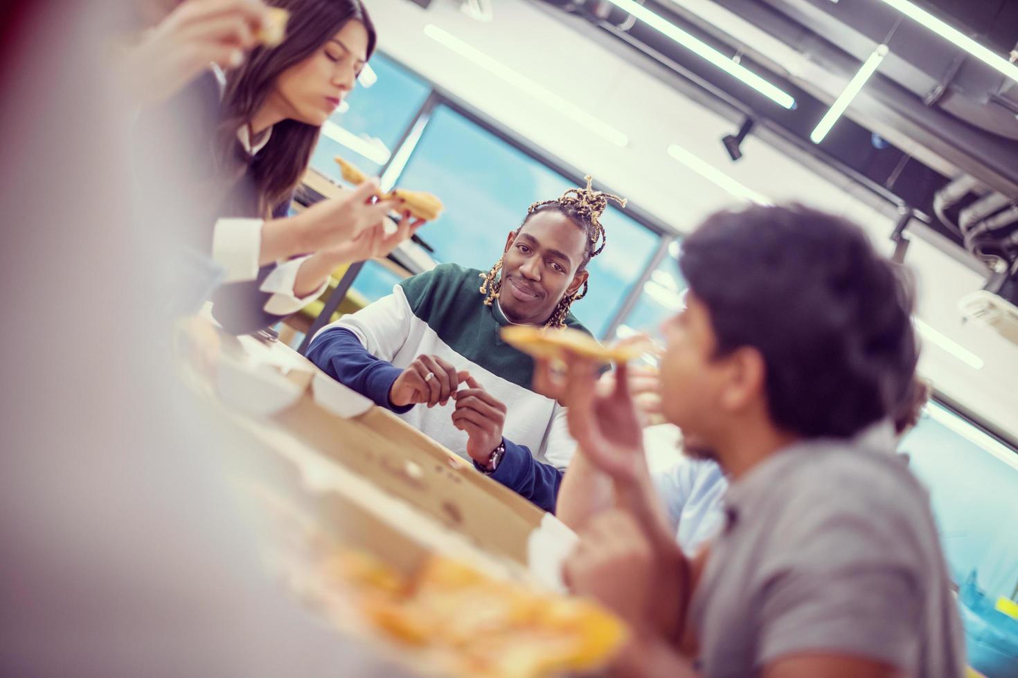 multiethnic business team eating pizza photo