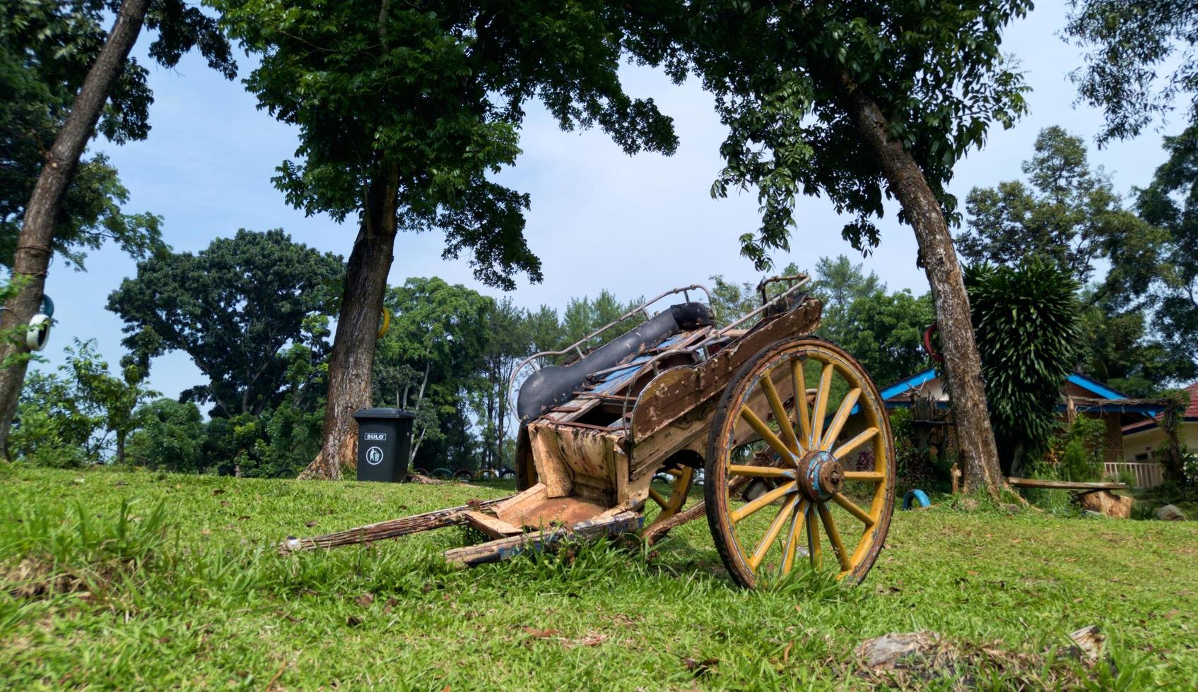 an old and broken horse carriage that was abandoned in a garden photo