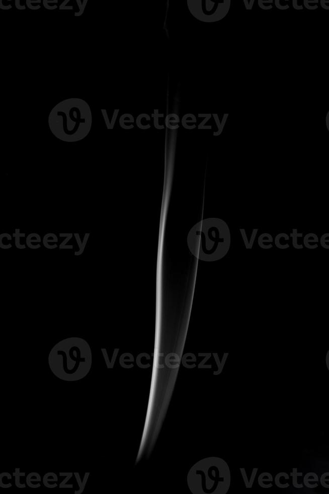 A single white smoke burn from incense, shot in studio with dark black background, for design and religion concept photo