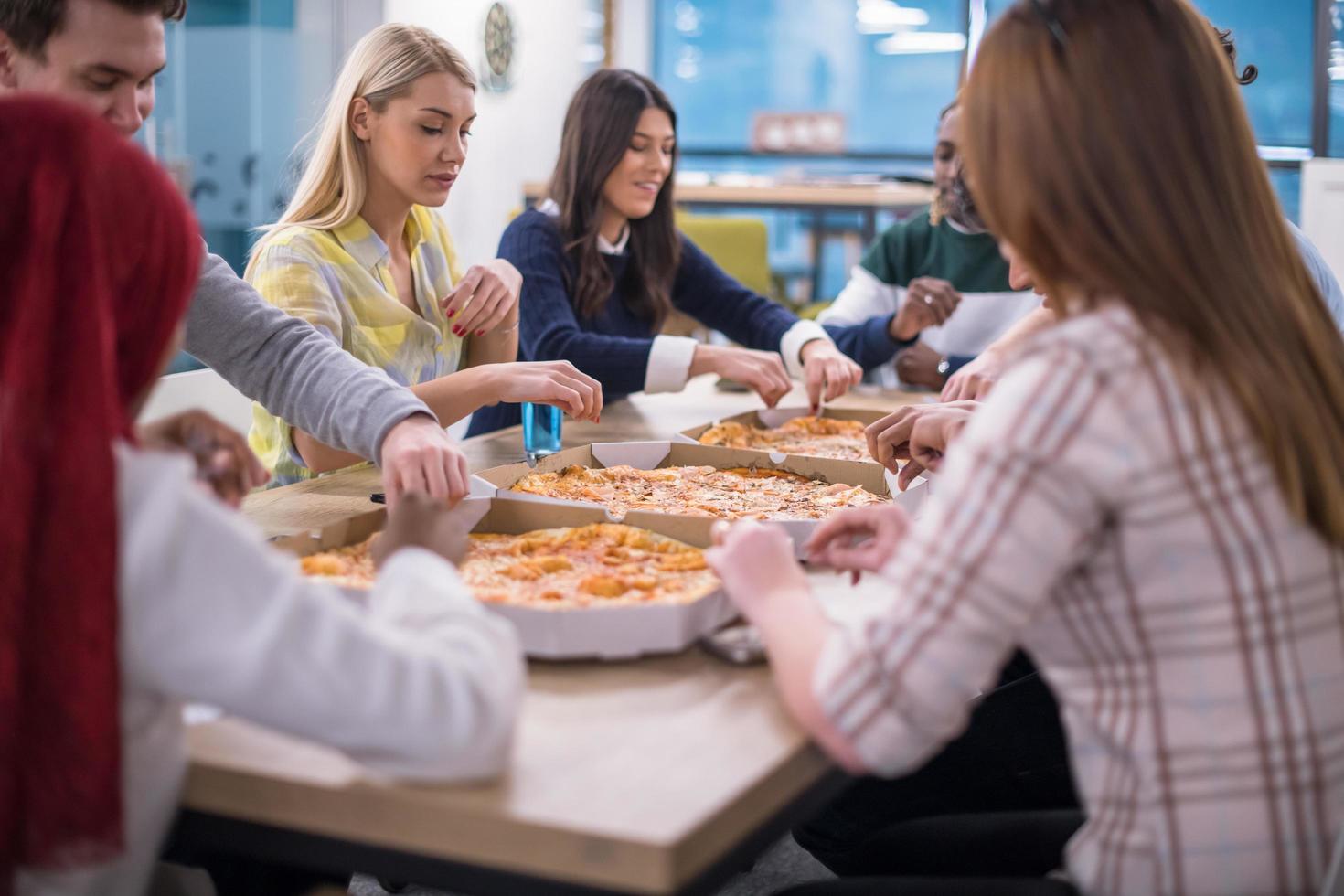 multiethnic business team eating pizza photo