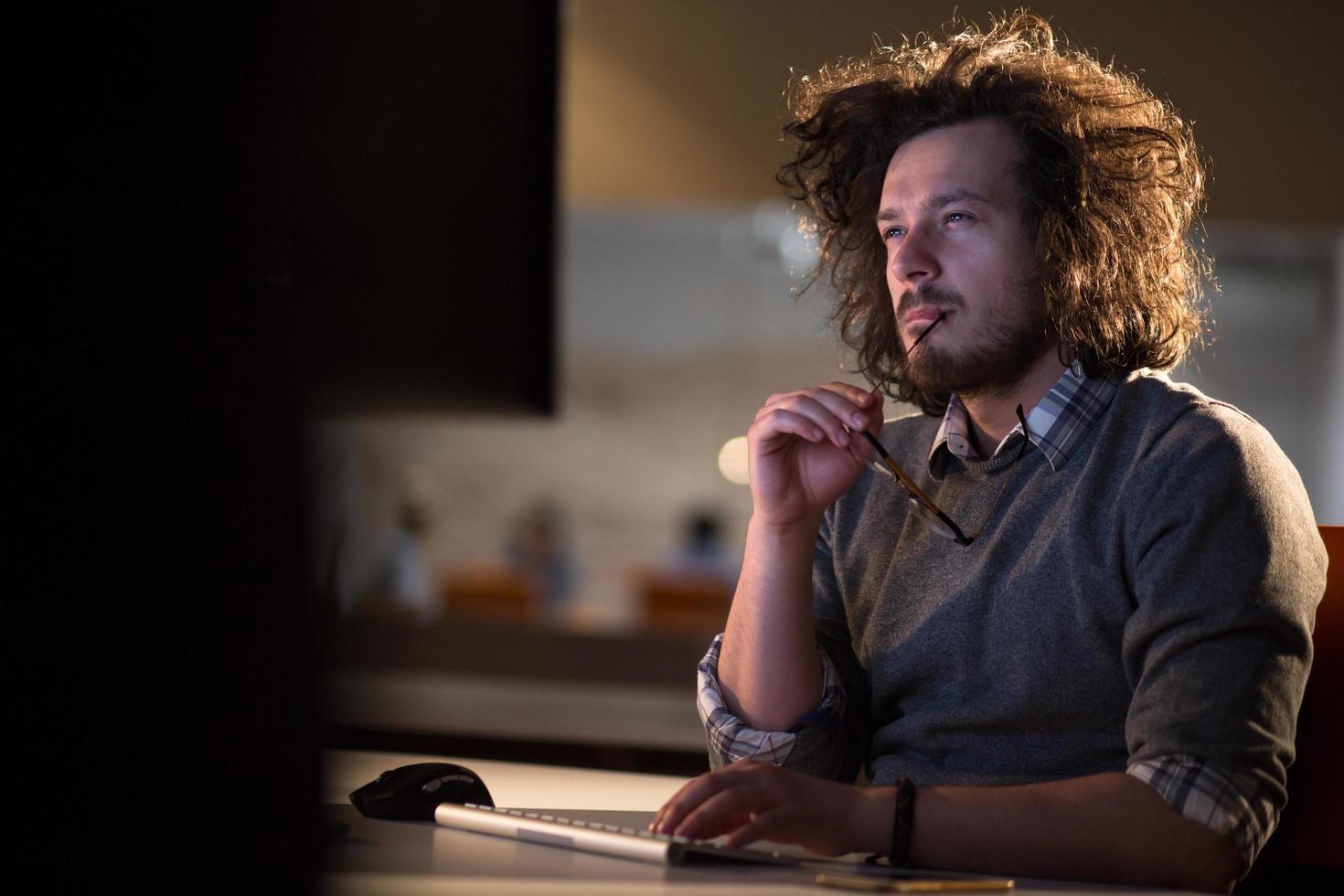 man working on computer in dark office photo