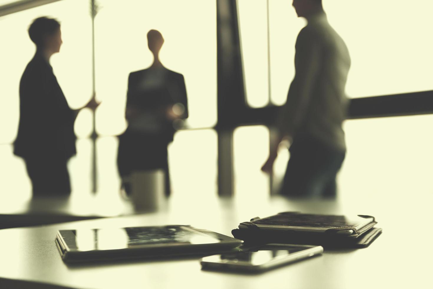 close up of tablet, business people on meeting in background photo