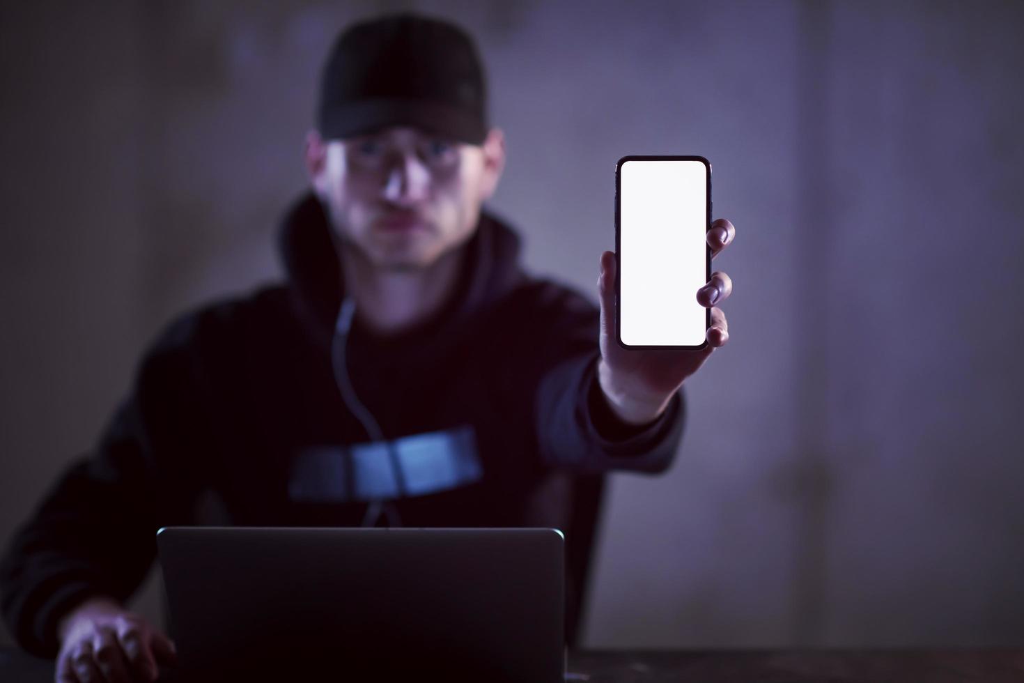 criminal hacker using laptop computer while working in dark office photo