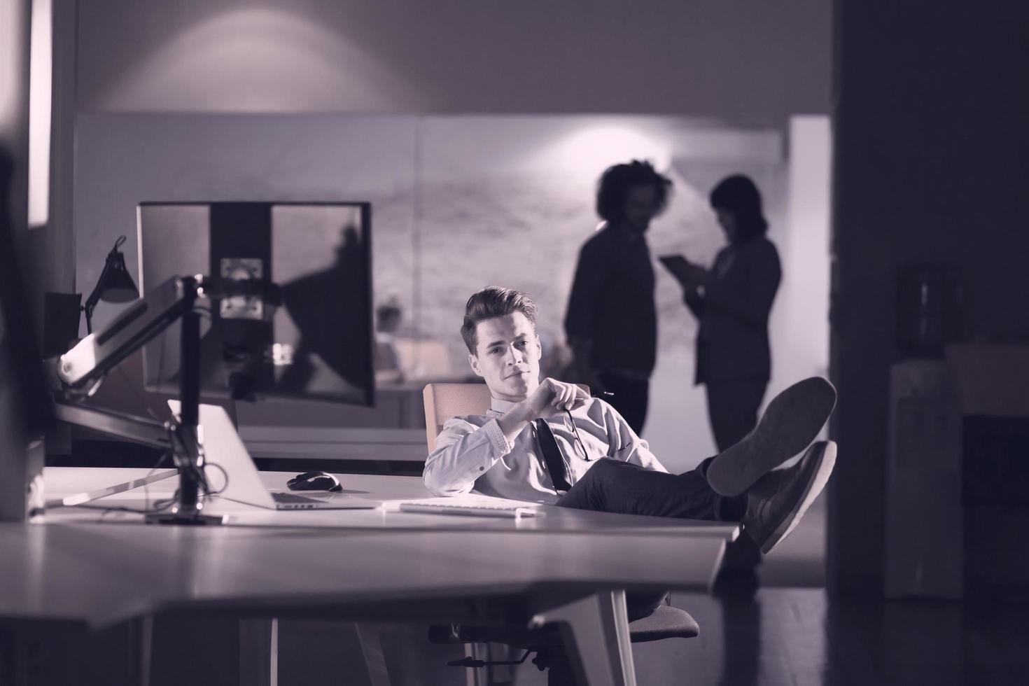 businessman sitting with legs on desk at office photo
