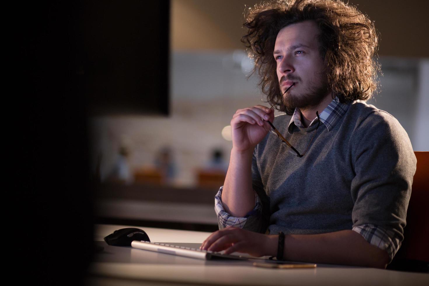 hombre trabajando en una computadora en una oficina oscura foto