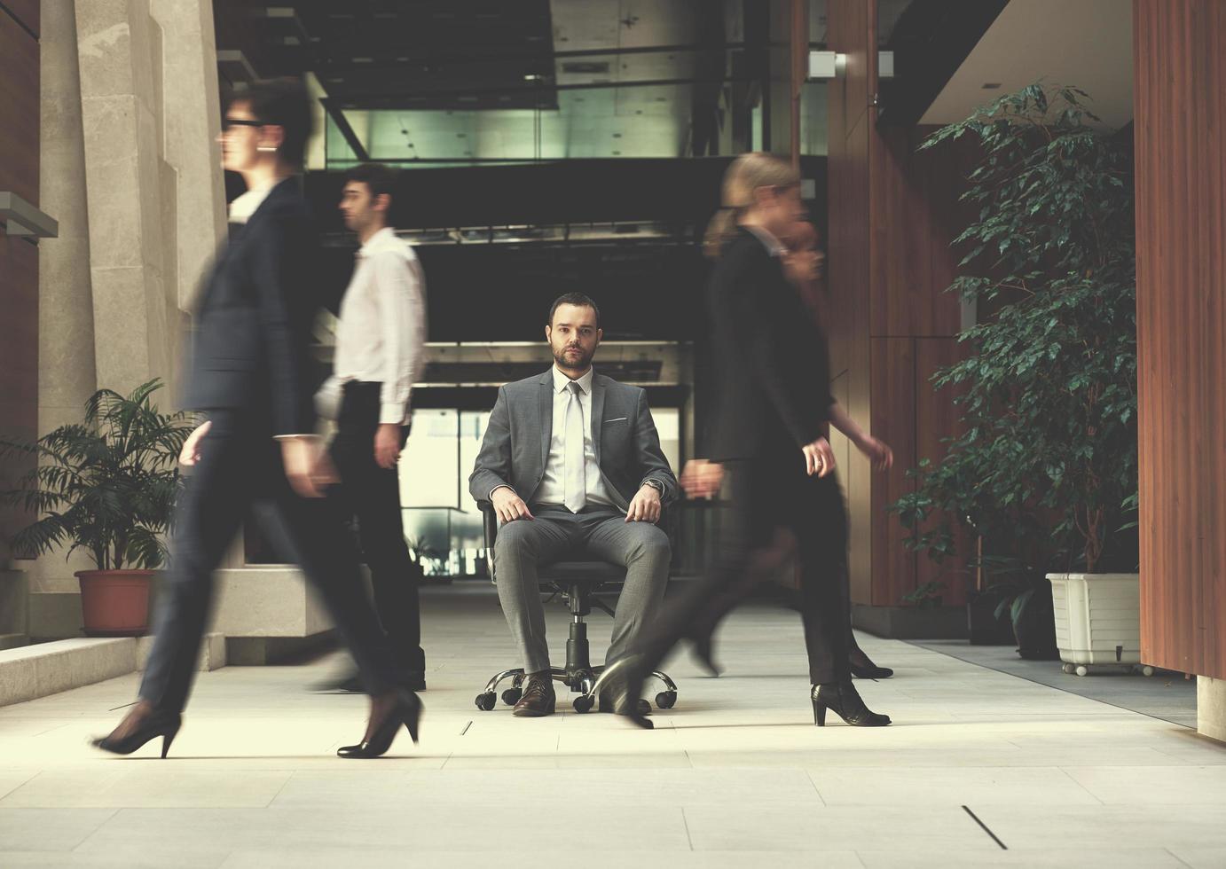 business man sitting in office chair, people group  passing by photo