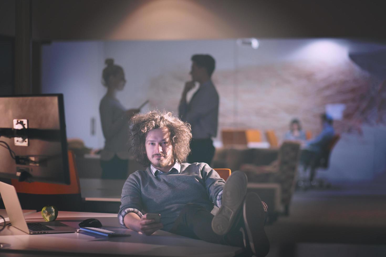 businessman sitting with legs on desk at office photo