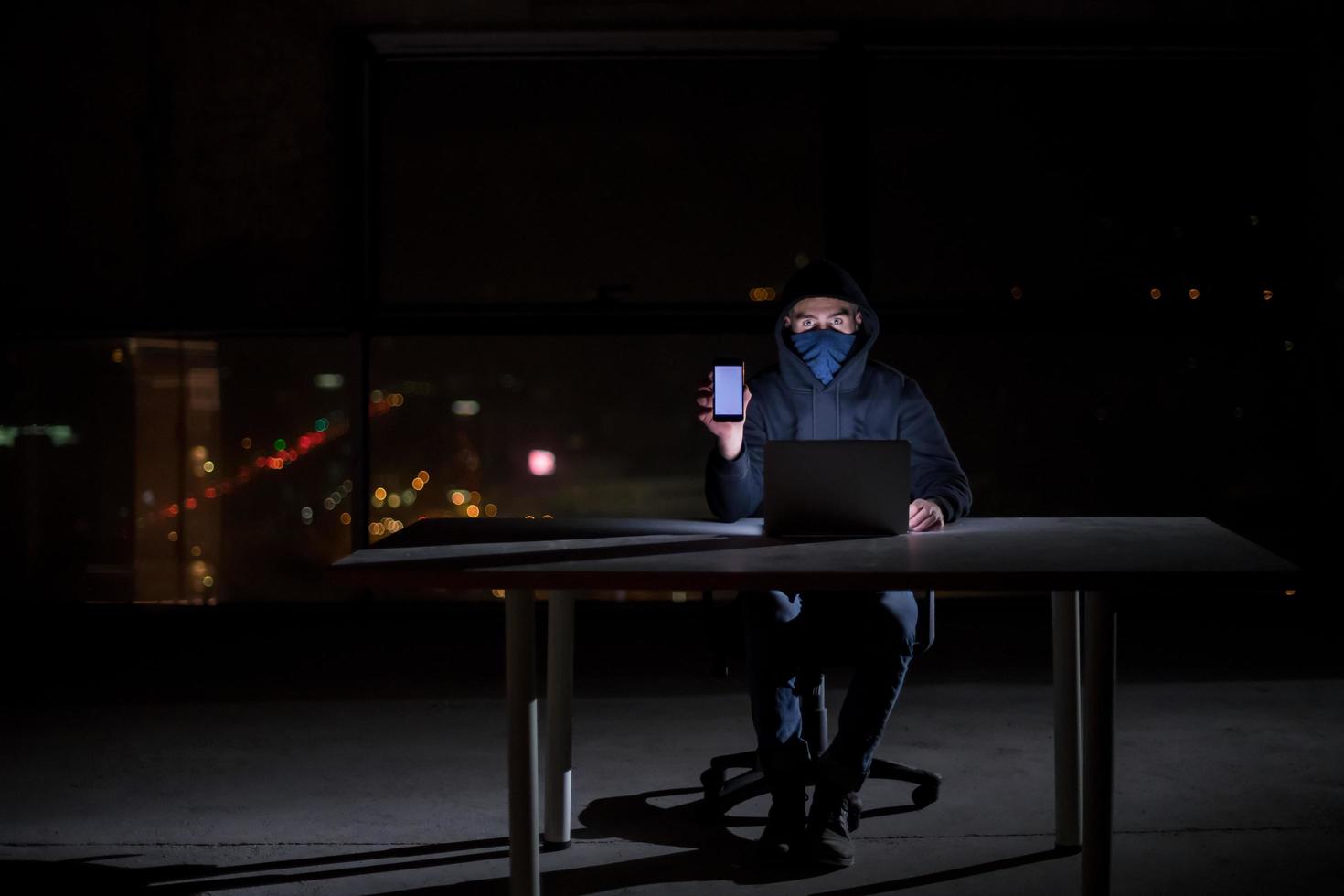 hacker using laptop computer while working in dark office photo