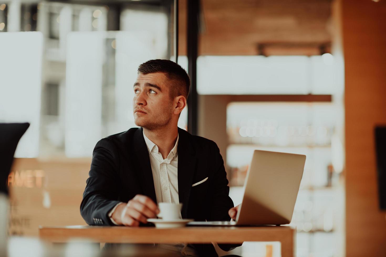 hombre de negocios feliz sentado en la cafetería con laptop y teléfono inteligente foto