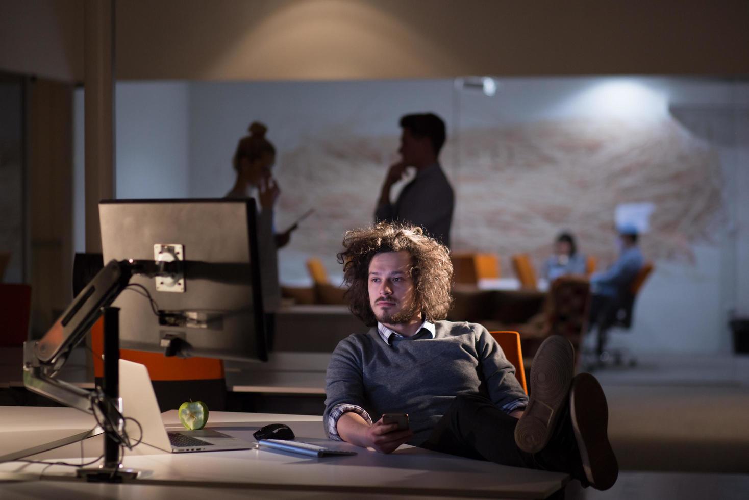 businessman sitting with legs on desk at office photo