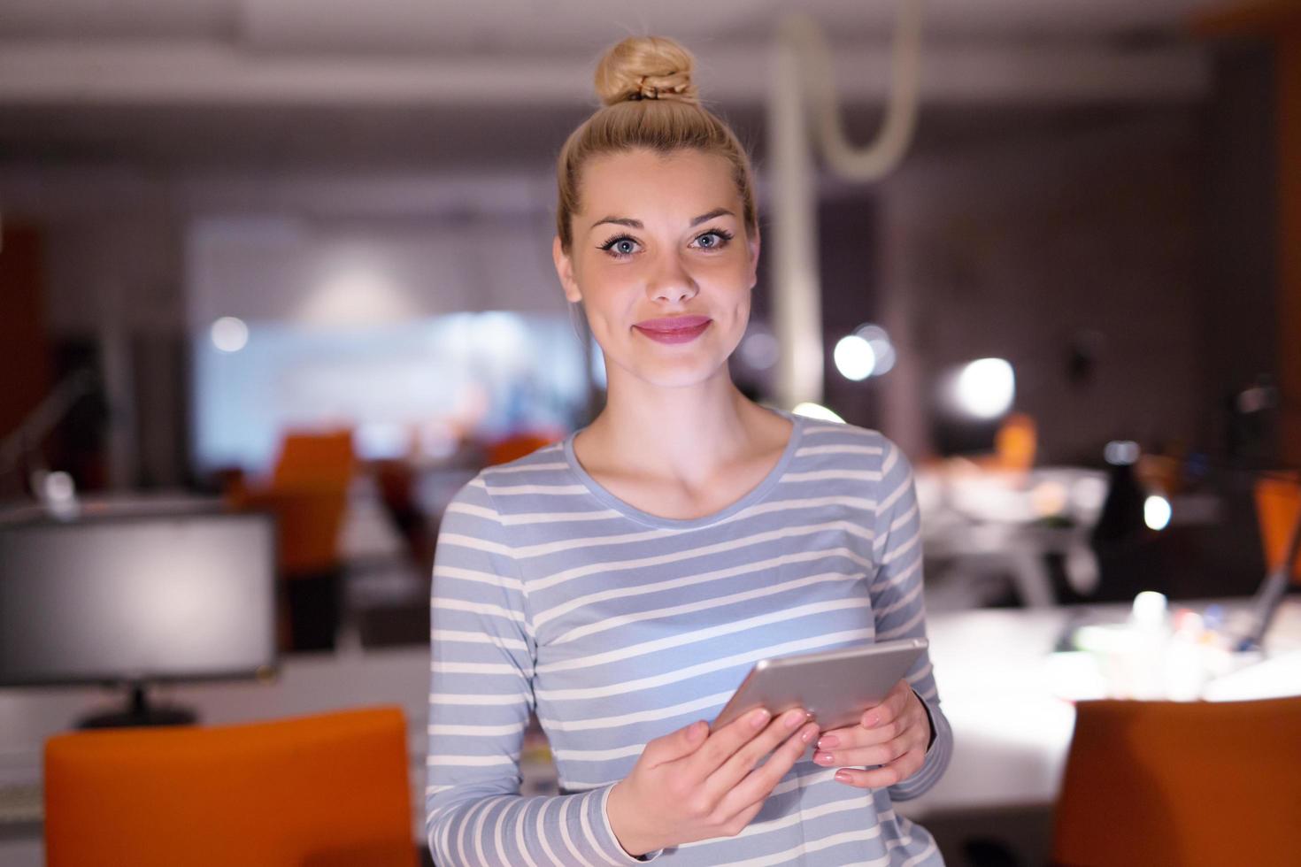 woman working on digital tablet in night office photo
