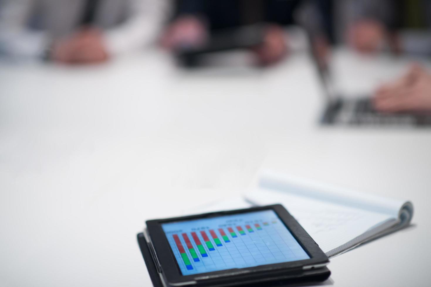 close up of touchpad with analytics documents at business meeting photo