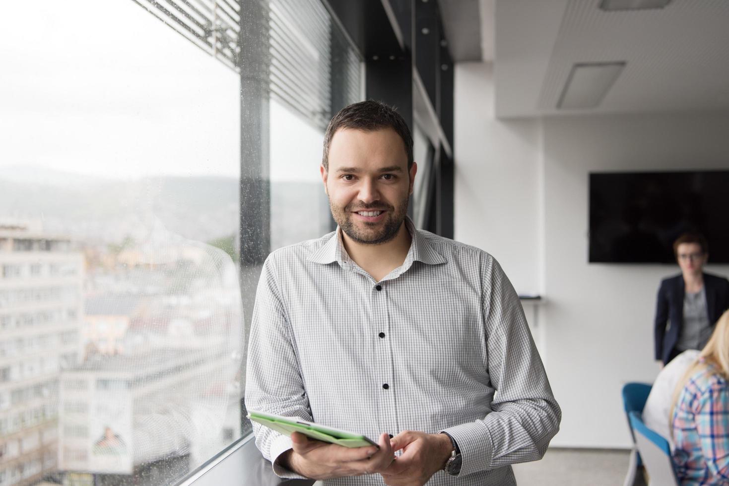 Businessman Using Tablet In Office Building by window photo