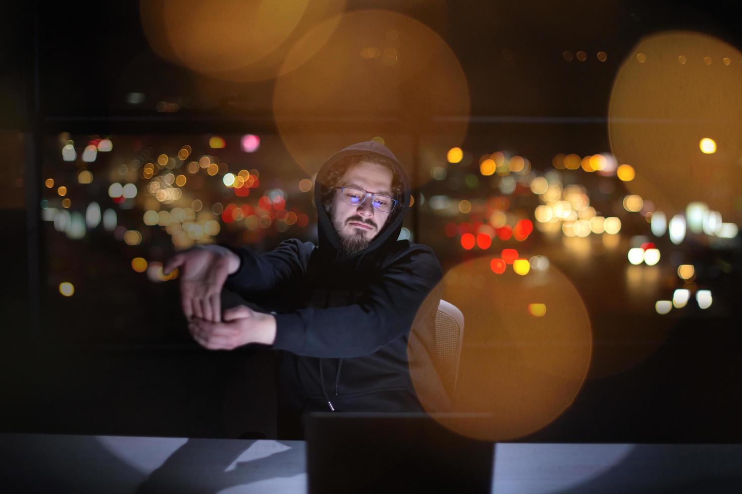 hacker using laptop computer while working in dark office photo