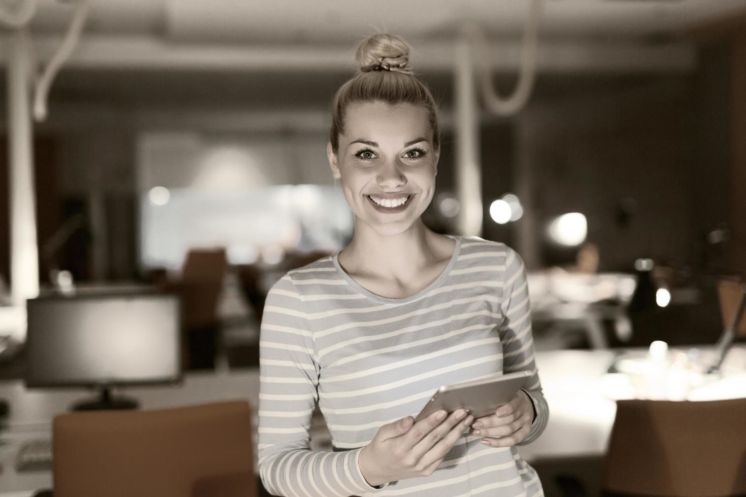 mujer que trabaja en una tableta digital en la oficina nocturna foto