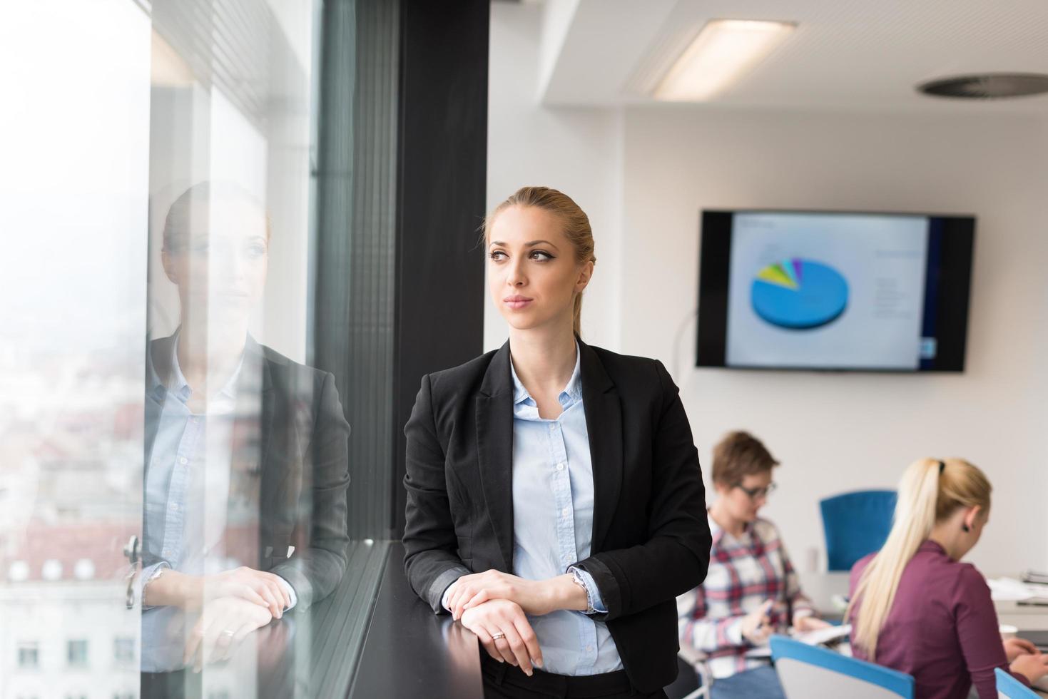 portrait of young business woman at office with team on meeting in background photo