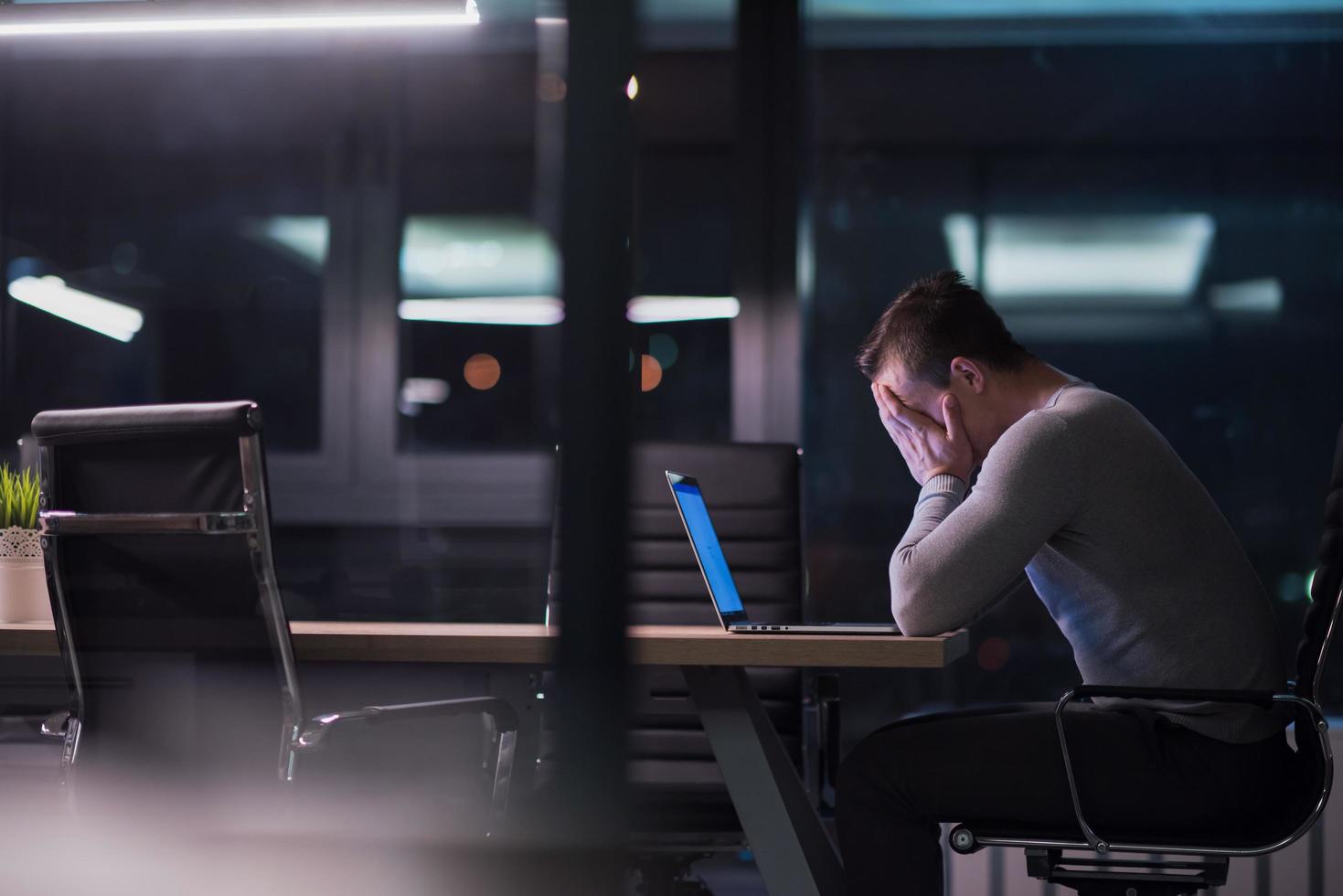 man working on laptop in dark office photo