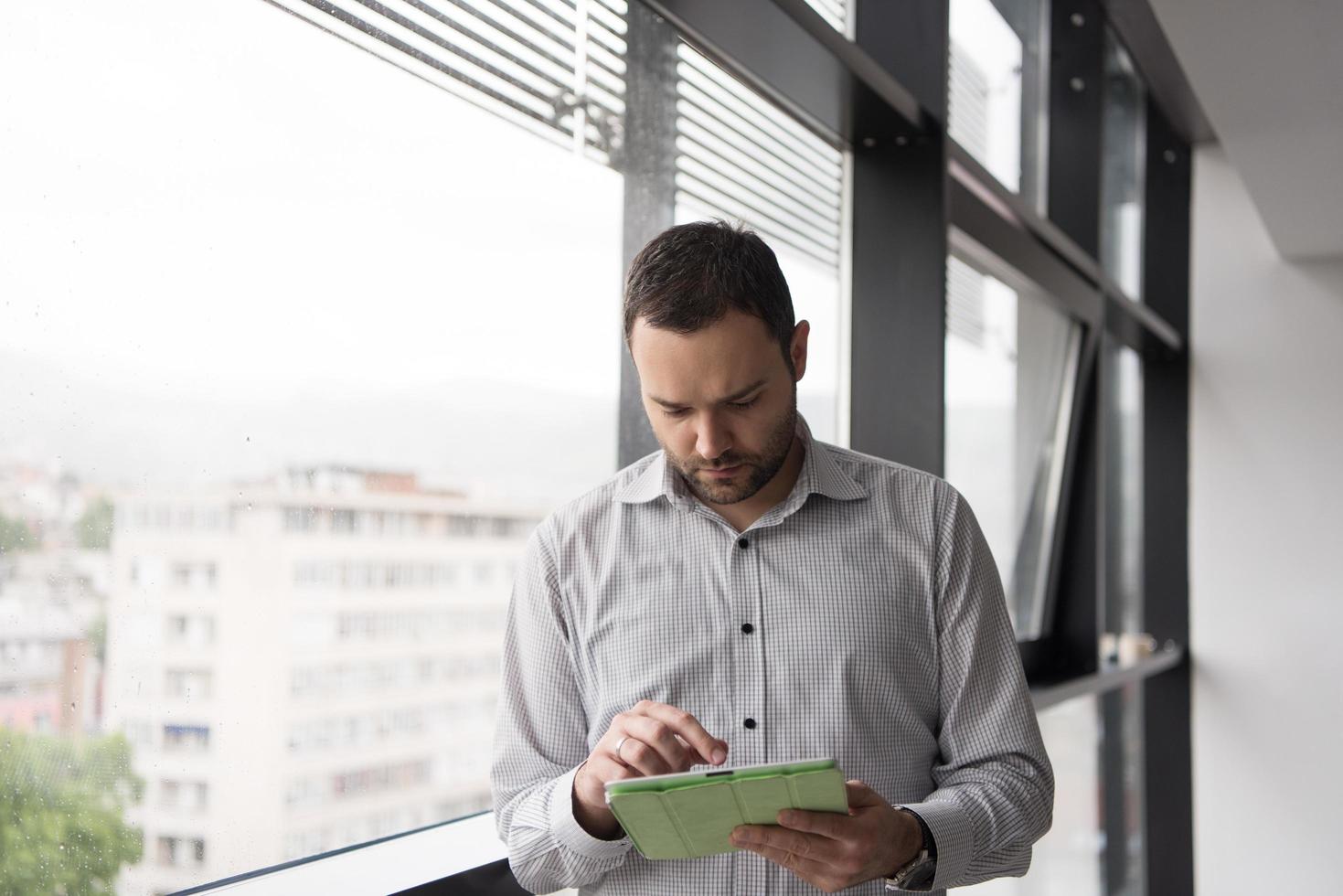 Businessman Using Tablet In Office Building by window photo
